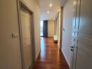 Hallway with wooden floor and closed doors leading to living areas