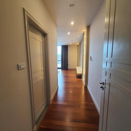 Hallway with wooden floor and closed doors leading to living areas