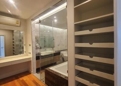 Modern bathroom with a glass-enclosed shower, bathtub, and open shelving