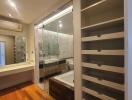 Modern bathroom with a glass-enclosed shower, bathtub, and open shelving