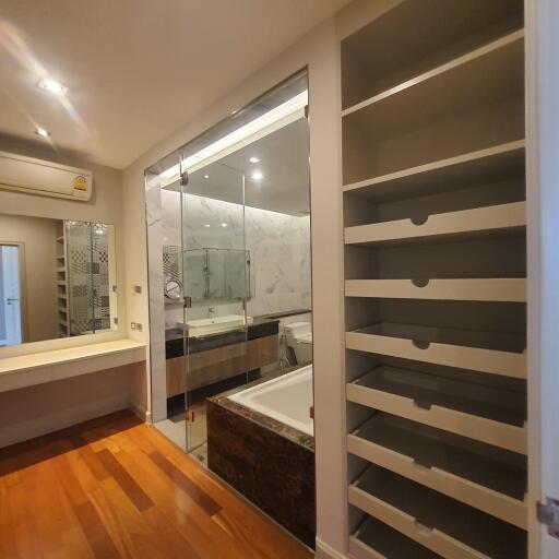 Modern bathroom with a glass-enclosed shower, bathtub, and open shelving