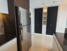 Modern kitchen with stainless steel refrigerator, black and white cabinets, and tiled backsplash