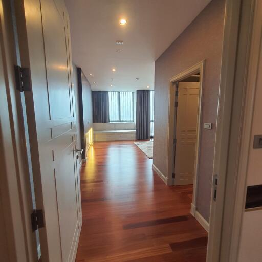 Living area with wooden flooring, large windows, and adjoining rooms