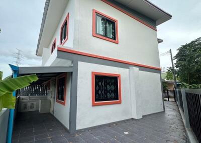 Exterior view of a two-story house with balcony and surrounding patio