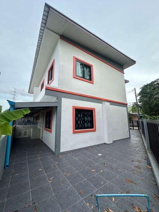 Exterior view of a two-story house with balcony and surrounding patio