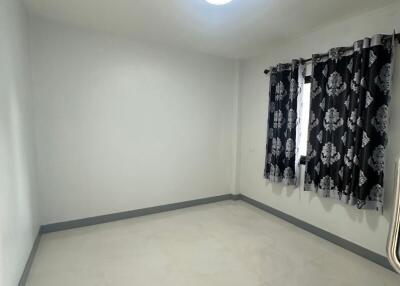 Empty bedroom with tiled flooring and patterned curtains