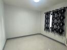 Empty bedroom with tiled flooring and patterned curtains