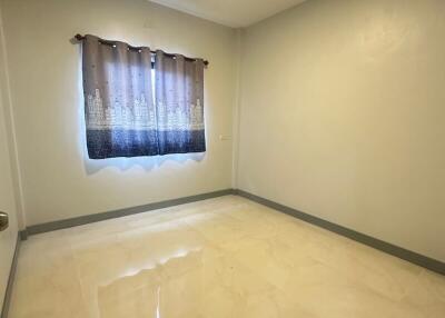 Empty bedroom with tiled floor and a curtained window