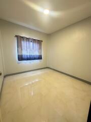 Empty bedroom with tiled floor and a curtained window