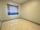 Empty bedroom with tiled floor and a curtained window