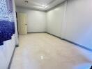 Spacious empty bedroom with white walls and tiled floors.