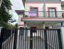 Front view of a two-story house with a balcony and a 'For Sale' sign