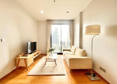 Modern living room with wooden floor, cream sofa, floor lamp, and TV on wooden table