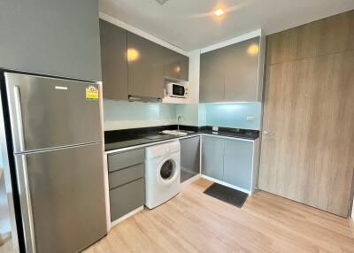 Modern kitchen with grey cabinets, black countertops, and wood flooring