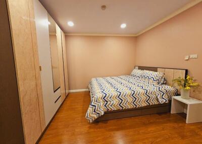 Modern bedroom with wooden floor, double bed, bedside table, and built-in wardrobe