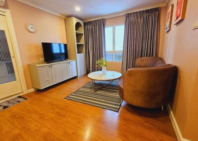 Cozy living room with wood flooring, a TV, and comfortable seating