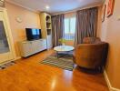 Cozy living room with wood flooring, a TV, and comfortable seating