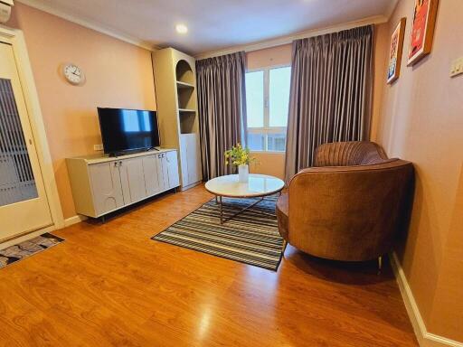 Cozy living room with wood flooring, a TV, and comfortable seating