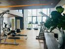 Modern fitness center with various exercise equipment and large windows