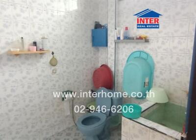 Bathroom with blue toilet, sink, mirror, and various toiletries