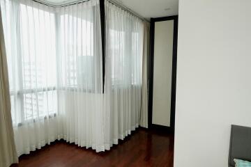 Bright bedroom corner with large windows and wooden floor