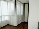 Bright bedroom corner with large windows and wooden floor