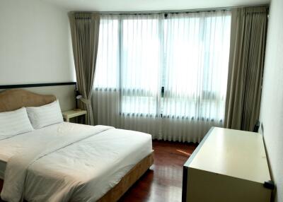 Spacious bedroom with a large window, bed, and side table