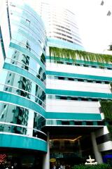 modern high-rise building with reflective glass windows and green accents