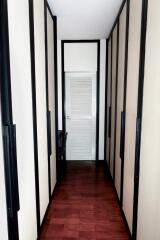 A narrow hallway with built-in storage and a door at the end