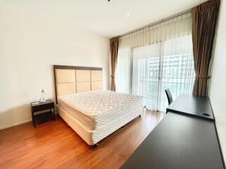 Well-lit bedroom with a large bed and study desk