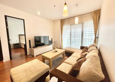 Modern living room with large sofa, TV, and large windows.