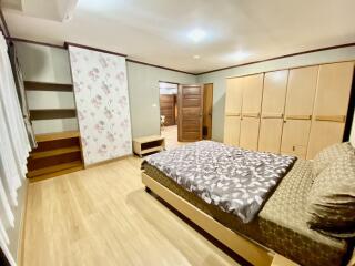 Spacious bedroom with large bed, wooden furniture, and built-in closet