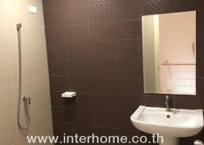 Modern bathroom with sink, shower, and brown tiled wall