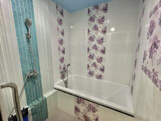 Bathroom with tub and floral tile design