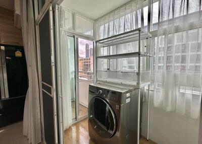 Bright laundry area with a washing machine and shelves