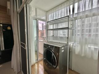 Bright laundry area with a washing machine and shelves