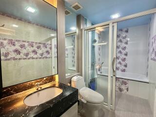 Modern bathroom with floral tiles and glass-enclosed shower