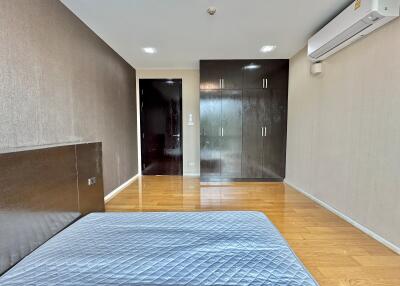 Spacious bedroom with wooden flooring, built-in wardrobe, air conditioning, and ample lighting.