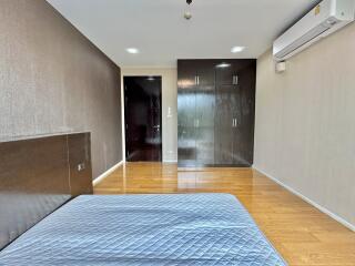 Spacious bedroom with wooden flooring, built-in wardrobe, air conditioning, and ample lighting.