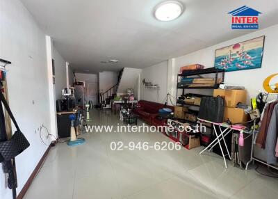 Spacious living room with tiled floor and various furniture items, including a sofa, shelves, and exercise equipment.