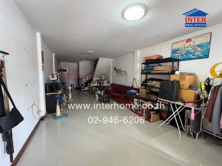 Spacious living room with tiled floor and various furniture items, including a sofa, shelves, and exercise equipment.