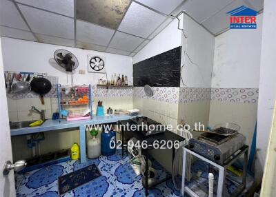 Compact and functional kitchen space with blue flooring and white tiled walls.