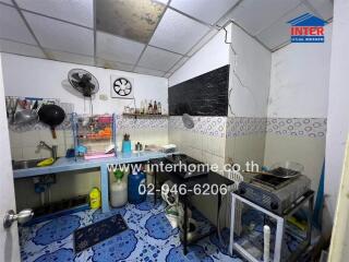 Compact and functional kitchen space with blue flooring and white tiled walls.