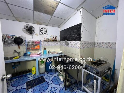 Compact and functional kitchen space with blue flooring and white tiled walls.