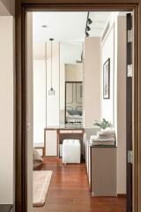 Modern bedroom view through open door with wooden flooring, stylish decor, and natural light