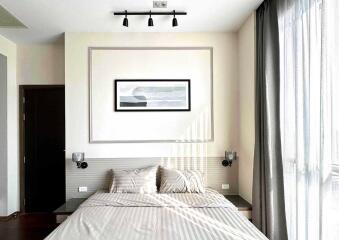 Well-lit modern bedroom with artwork and grey curtains