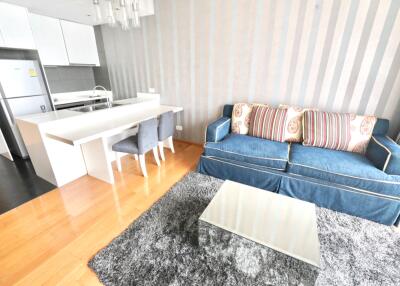 Modern living room and kitchen area with sofa, dining table, and chairs