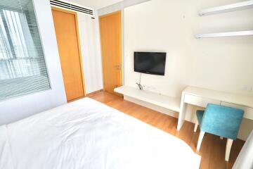 Modern bedroom with wooden floors and wall-mounted TV