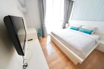 Modern bedroom with bed, TV, and large window