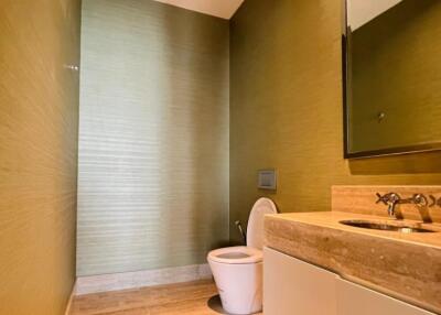 Modern bathroom with green textured walls, floating vanity, and wall-mounted toilet.